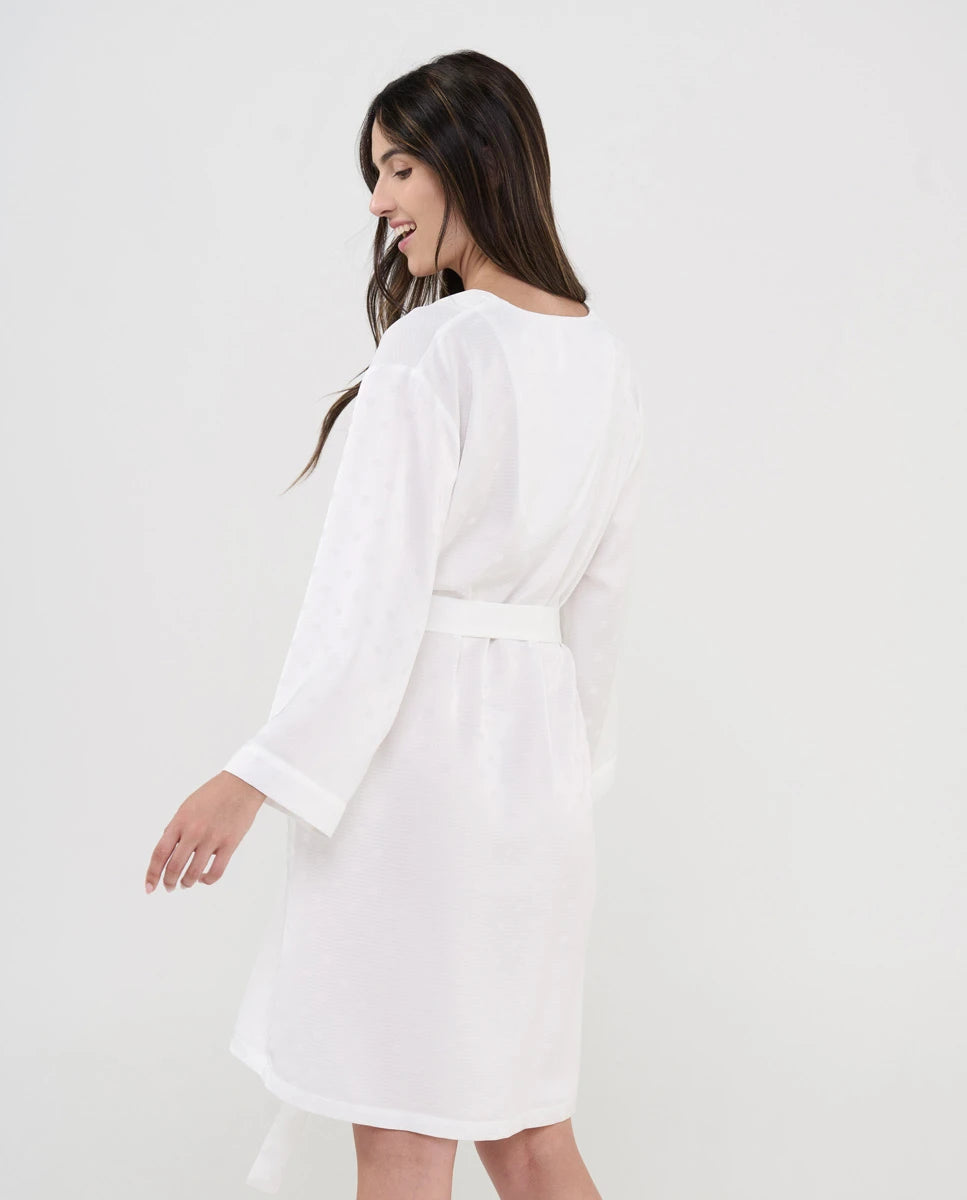 Vista lateral de mujer con cómoda y fresca bata de verano marfil y topos raso