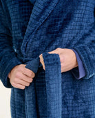 Hombre ajustándose el cinturón de una bata corta de casa jacquard azul marino