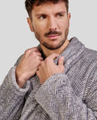 Hombre sujeta el cuello smoking de su elegante bata de espiga gris para invierno