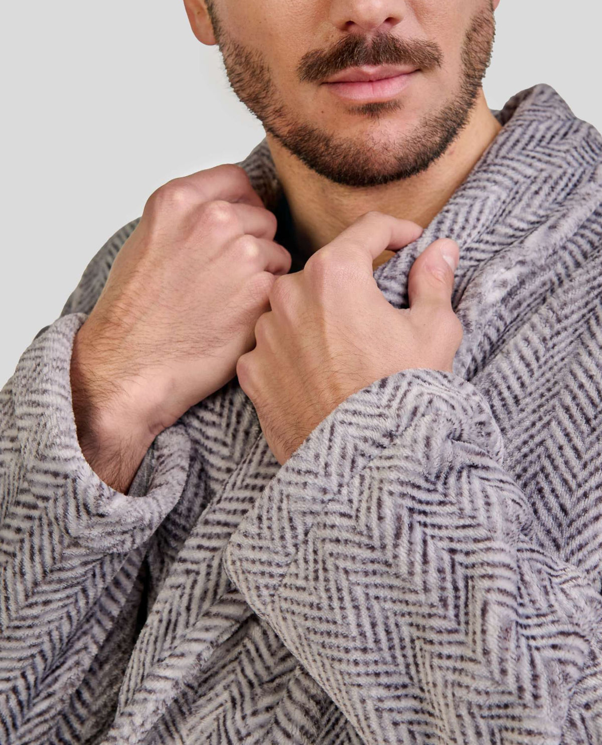 Hombre sujeta el cuello smoking de su elegante bata de espiga gris para invierno