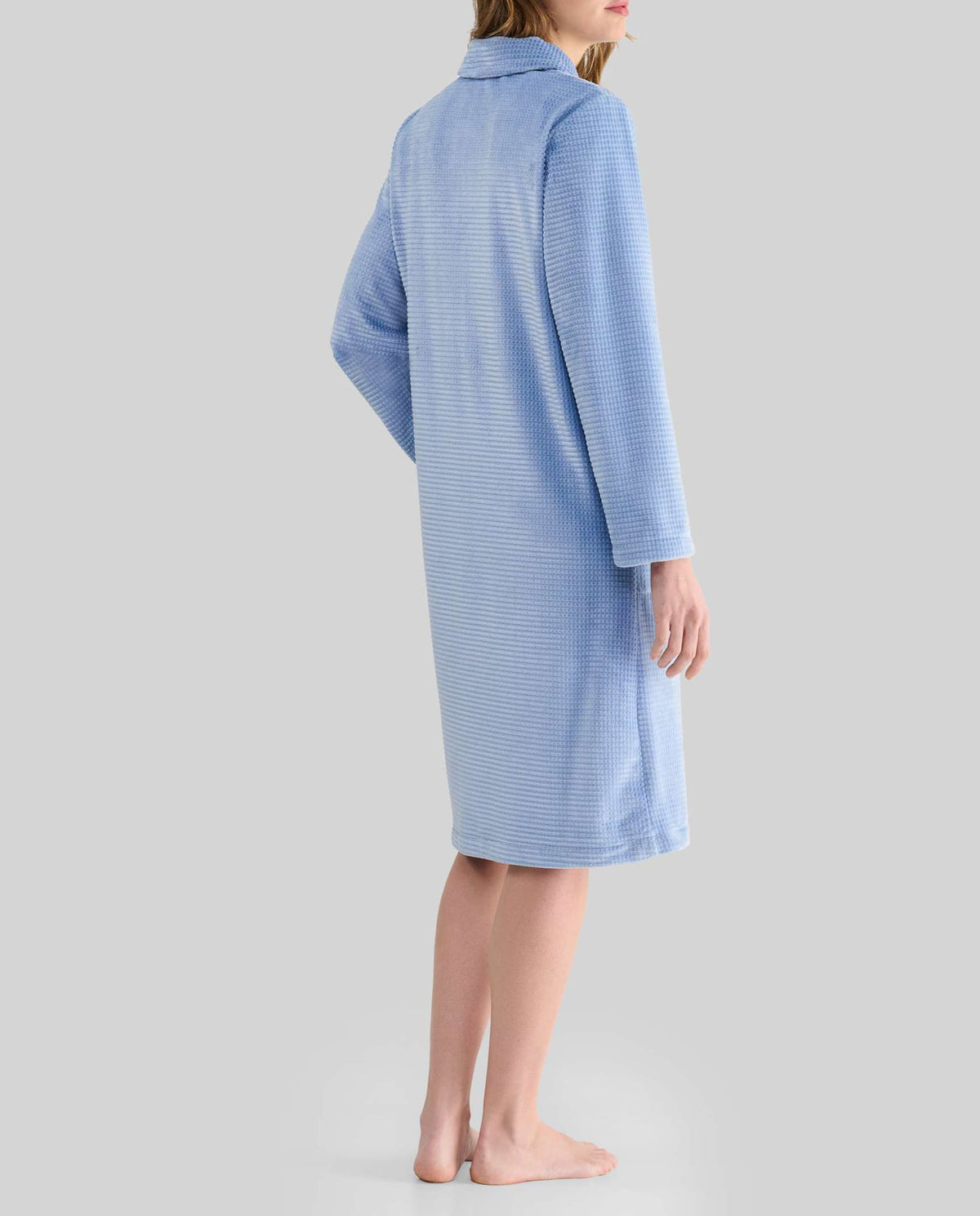 Mujer de espaldas luce bata larga de invierno jacquard azul con bolsillos