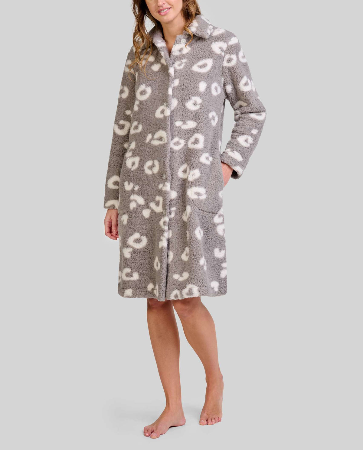Mujer luce bata polar gris hasta la rodilla con patrones animales blancos y dos bolsillos