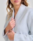 Mujer usando bata larga cruzada en elegante jacquard lanoso azul con cuello smoking