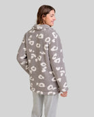 Mujer de espaldas con bata polar gris y blanca de leopardo y pantalón de pijama gris