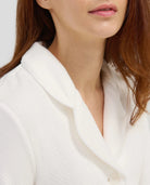 Vista detalle de bata de casa cruzada marfil con cinturón y bolsillos.