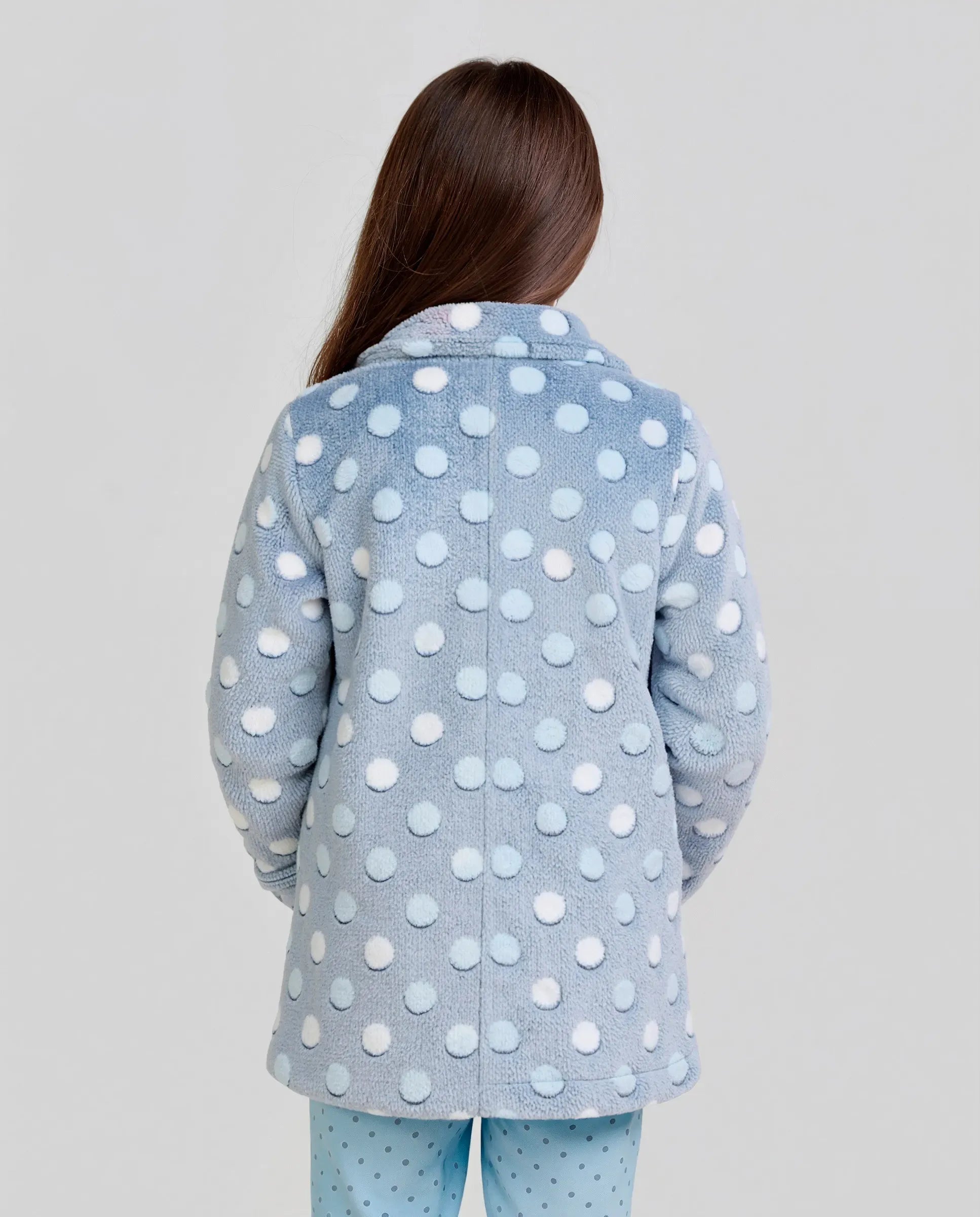 Vista lateral de niña posando con bata infantil de invierno estampada azul con círculos en relieve