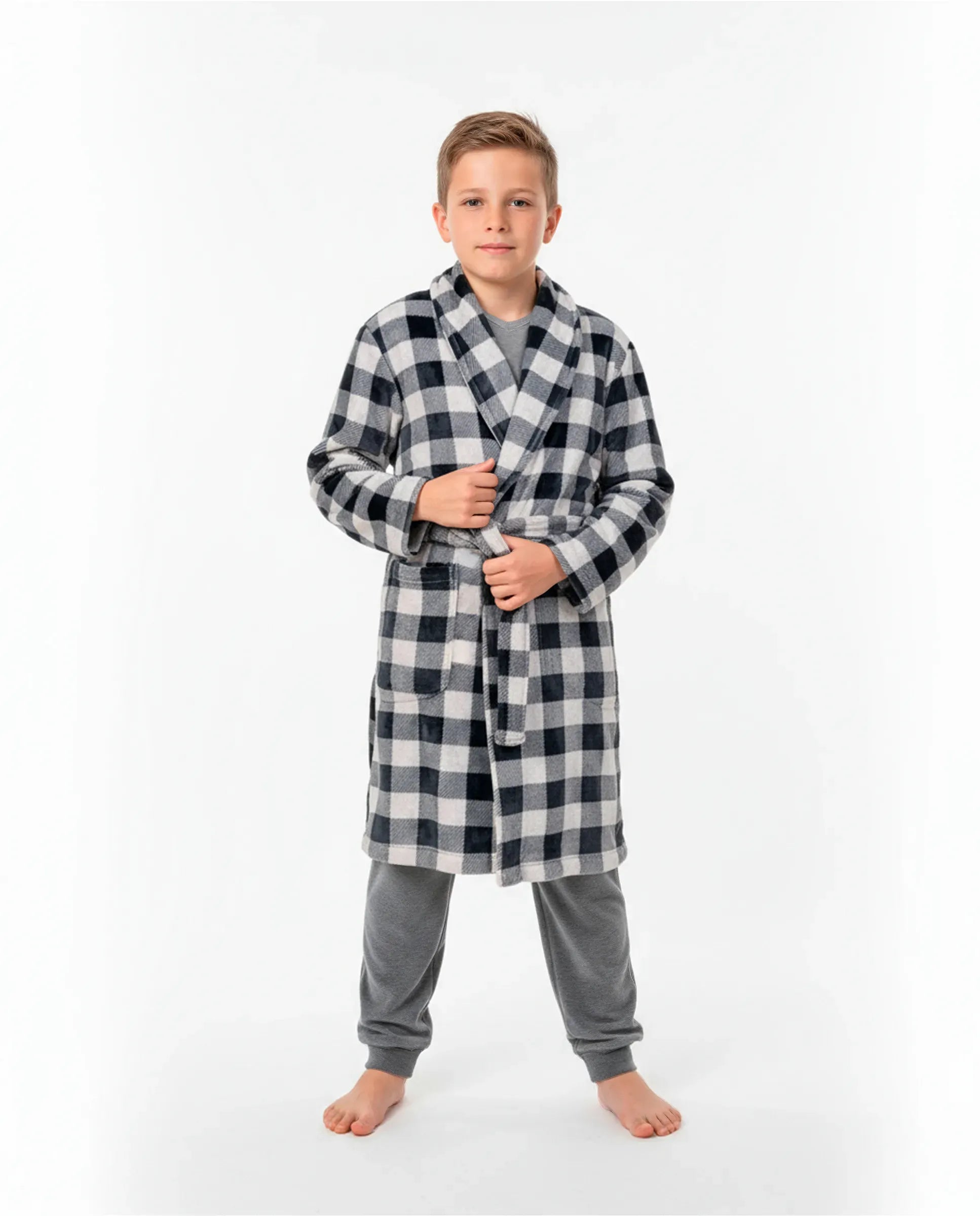 Niño con bata cruzada de invierno a cuadros negra y blanca sobre pijama gris de terciopelo