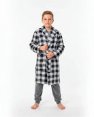 Niño con bata cruzada de invierno a cuadros negra y blanca sobre pijama gris de terciopelo