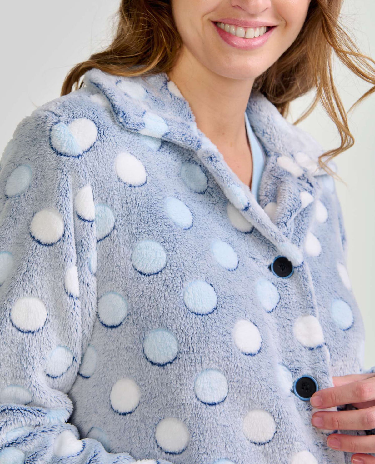 Mujer luce suave bata de invierno corta abotonada en azul claro con lunares