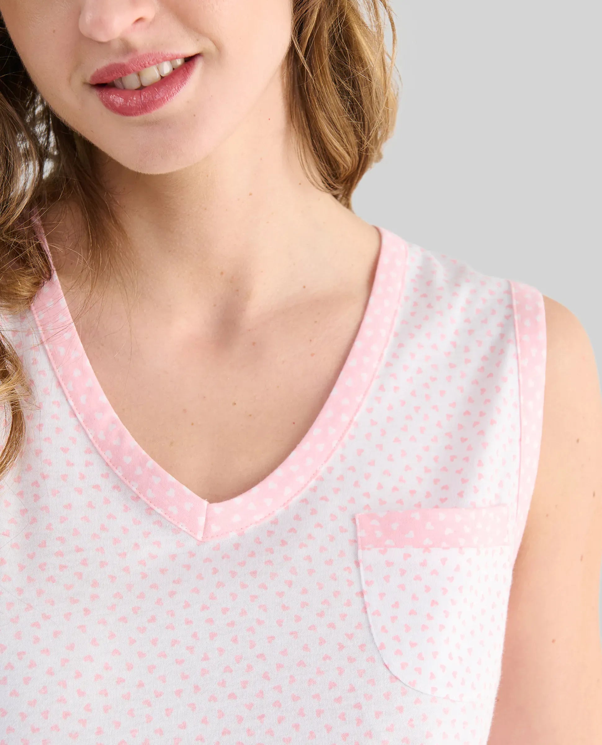 Mujer luce camisón lencero sin mangas de canalé rosa para verano con cuello abierto y entredos