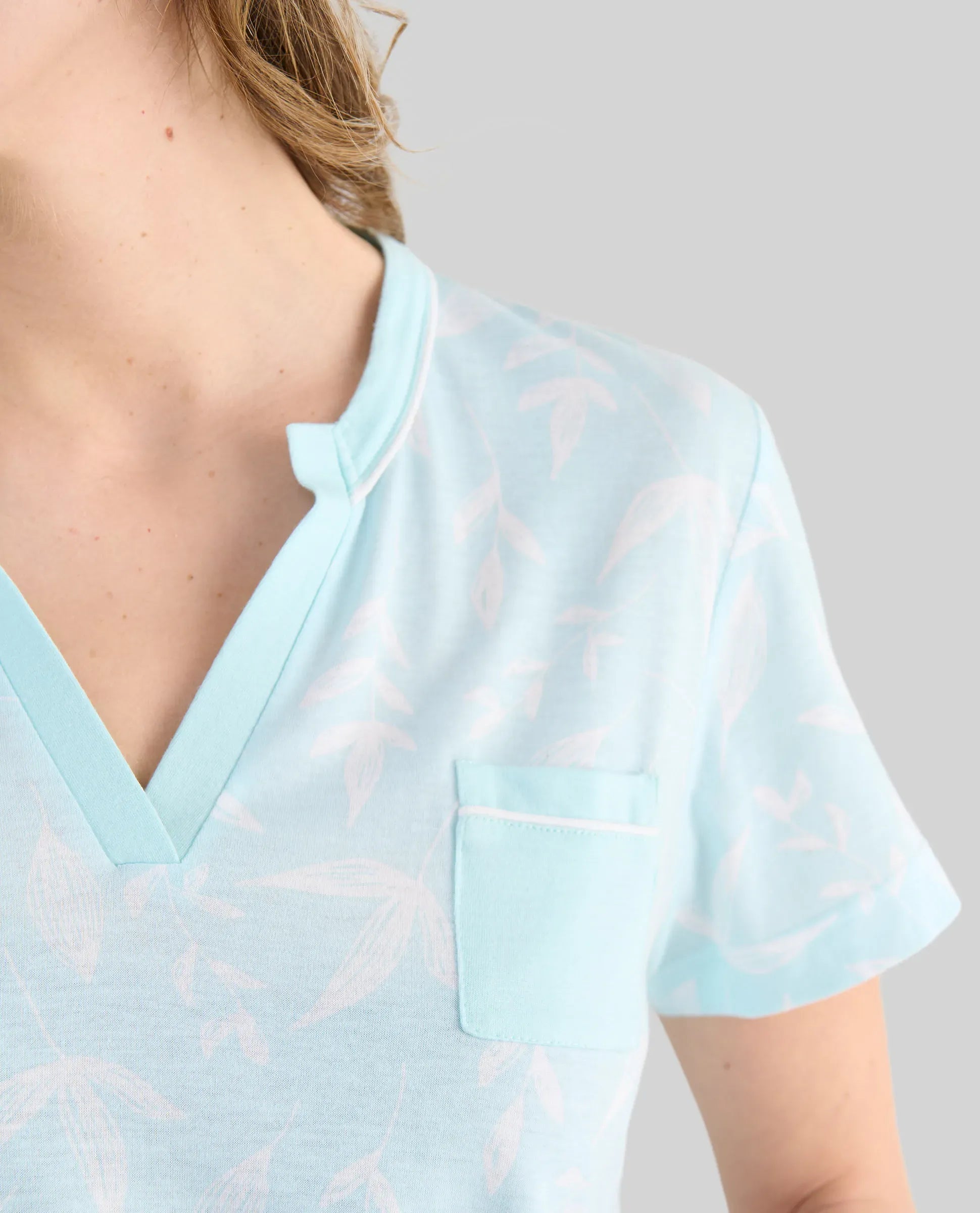 Detalle de cuello abierto de camisola de verano de manga corta verde estampada
