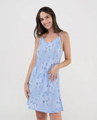 Mujer luce camisón corto de verano con tirantes finos estampado celeste de flores