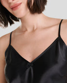 Detalle del escote en pico de camisón de tirantes en raso negro