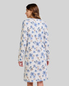 Mujer de espaldas luce camisón blanco de flores azules y beige hasta la rodilla con manga larga