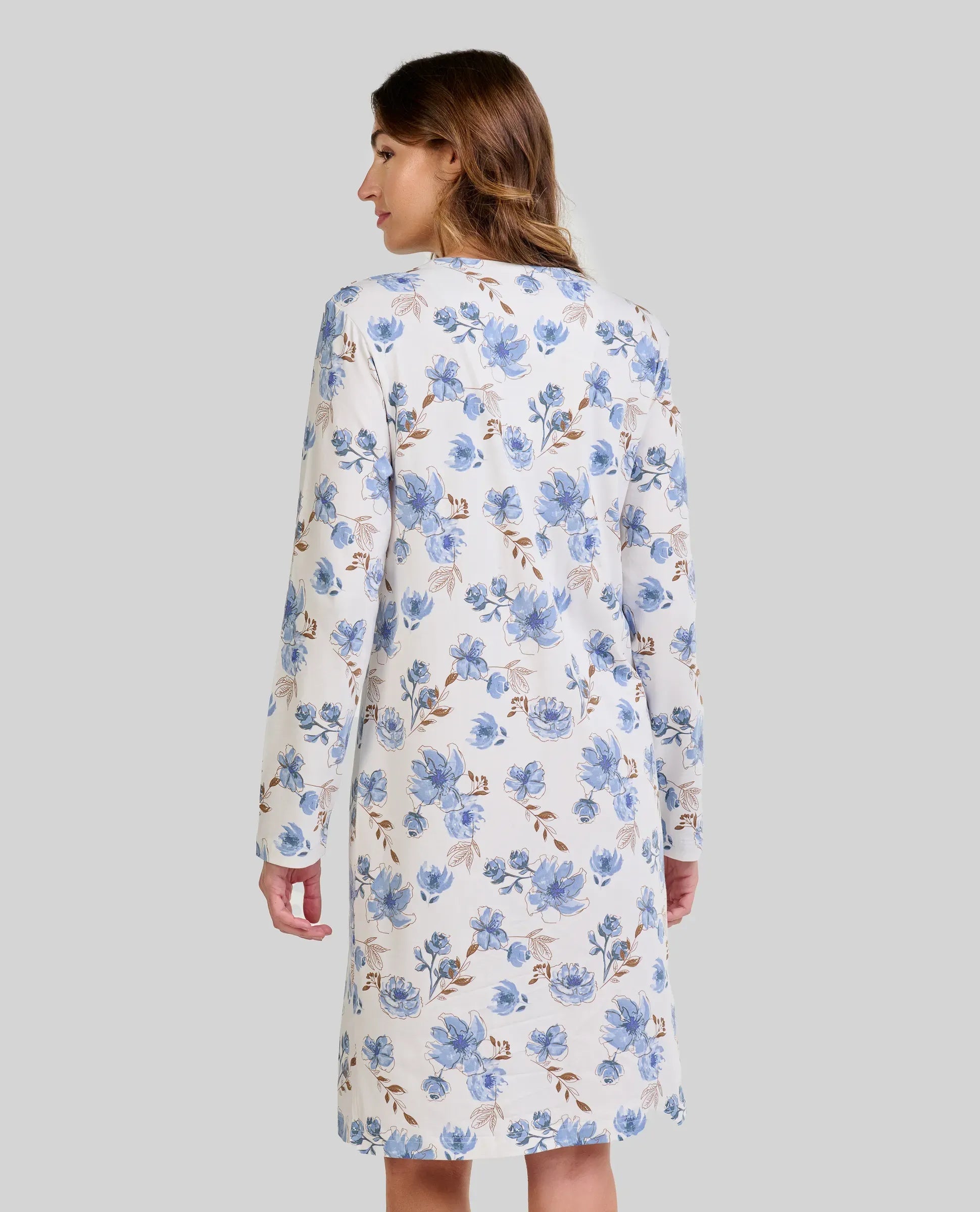 Mujer de espaldas luce camisón blanco de flores azules y beige hasta la rodilla con manga larga