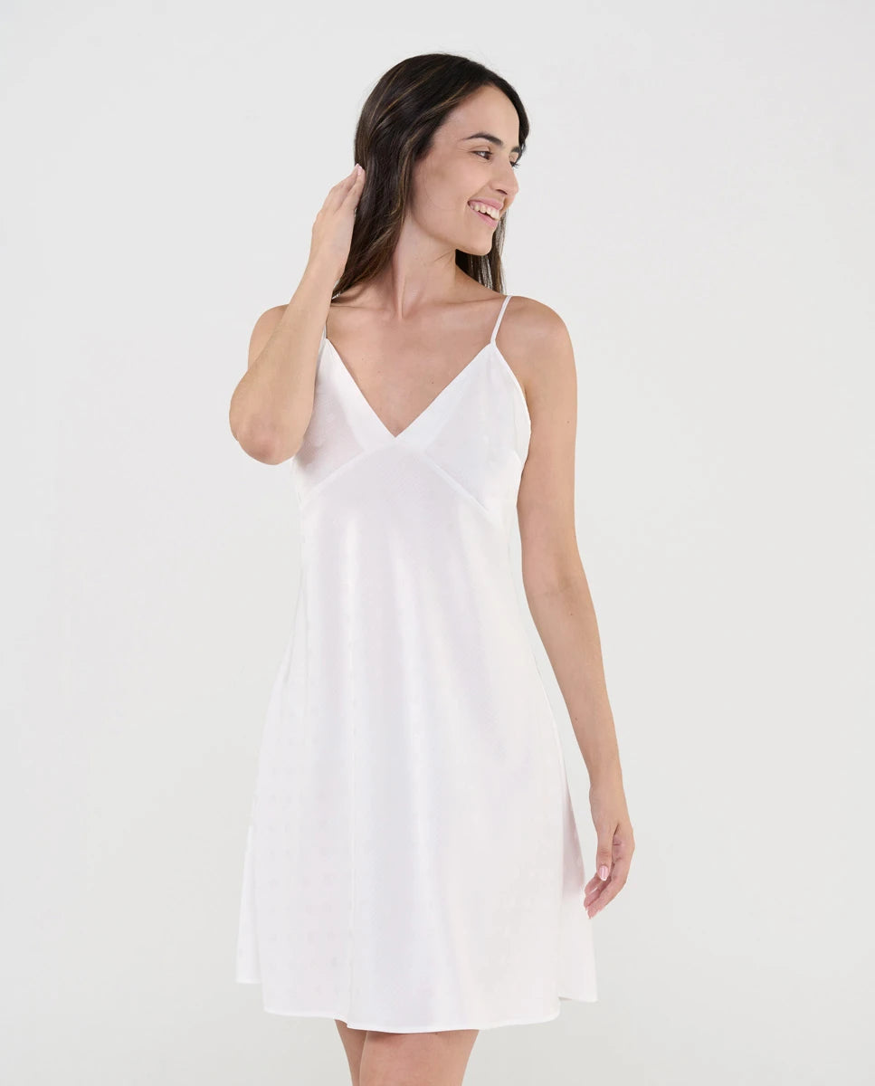 Mujer luce camisón lencero de suave tejido plana marfil con topos de raso, escote pico y tirantes