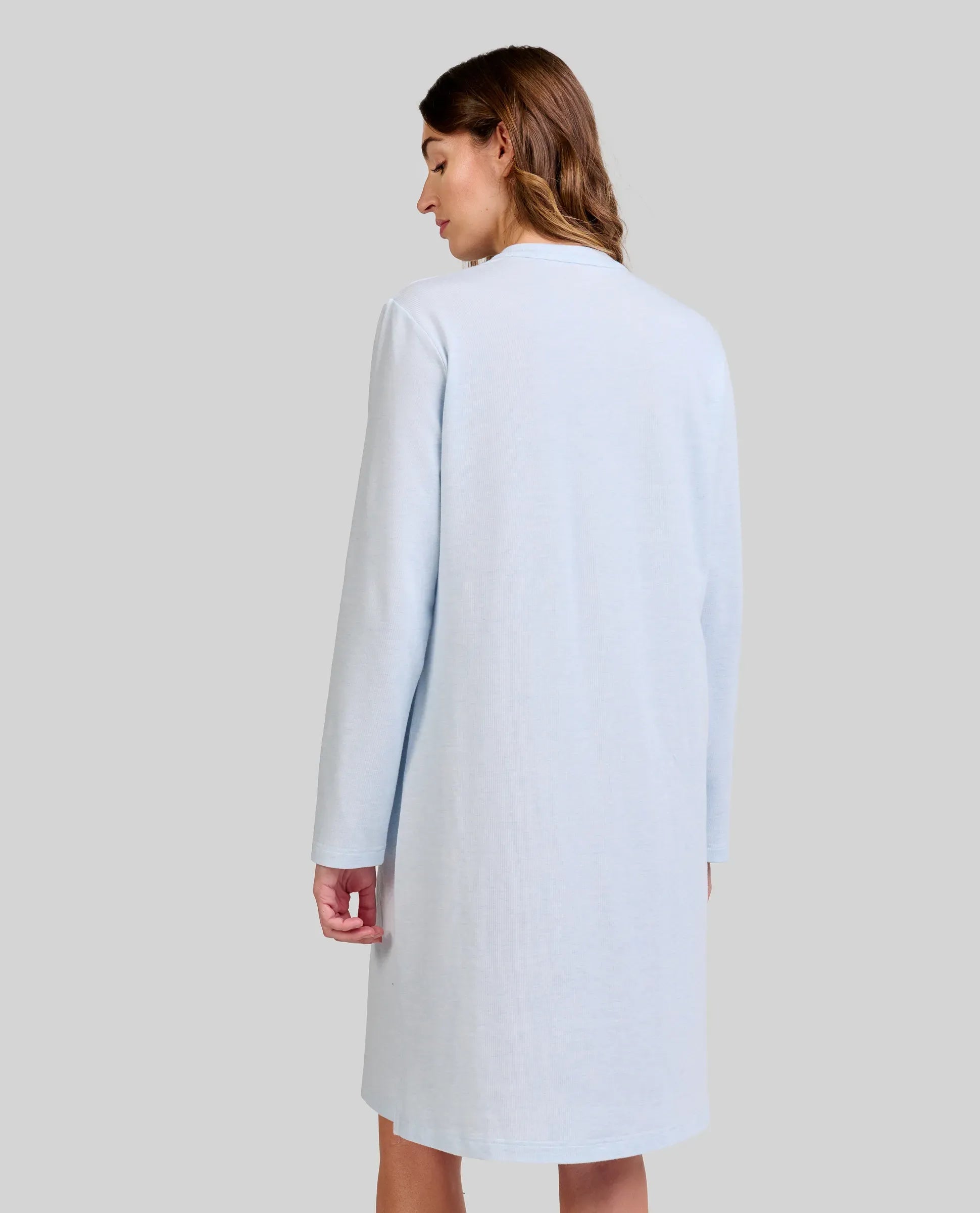 Mujer de espaldas con elegante camisola de invierno celeste de manga larga