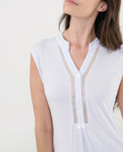 Detalle del cuello pata abotonado con entredós y lazo decorativo.