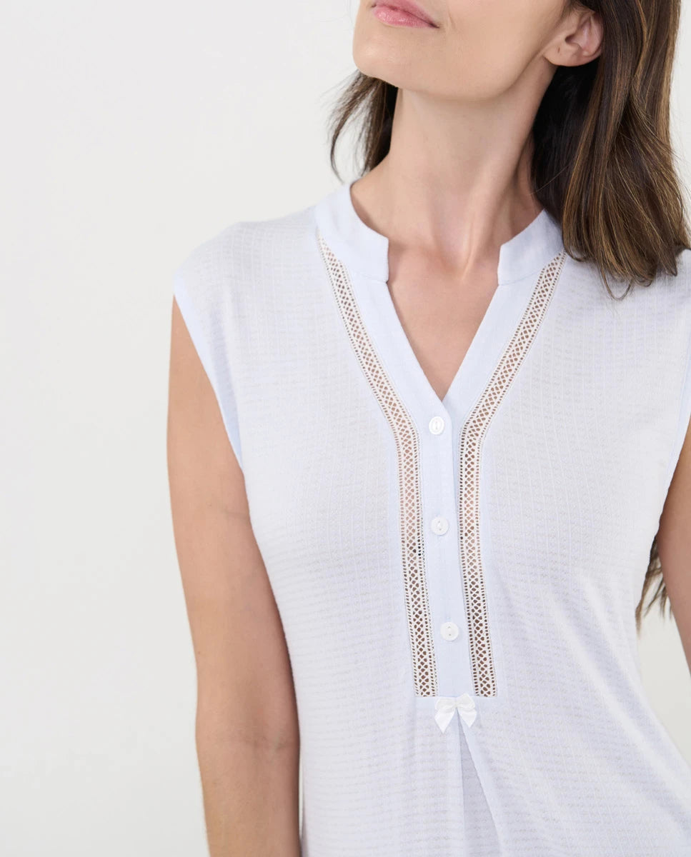 Detalle del cuello pata abotonado con entredós y lazo decorativo.