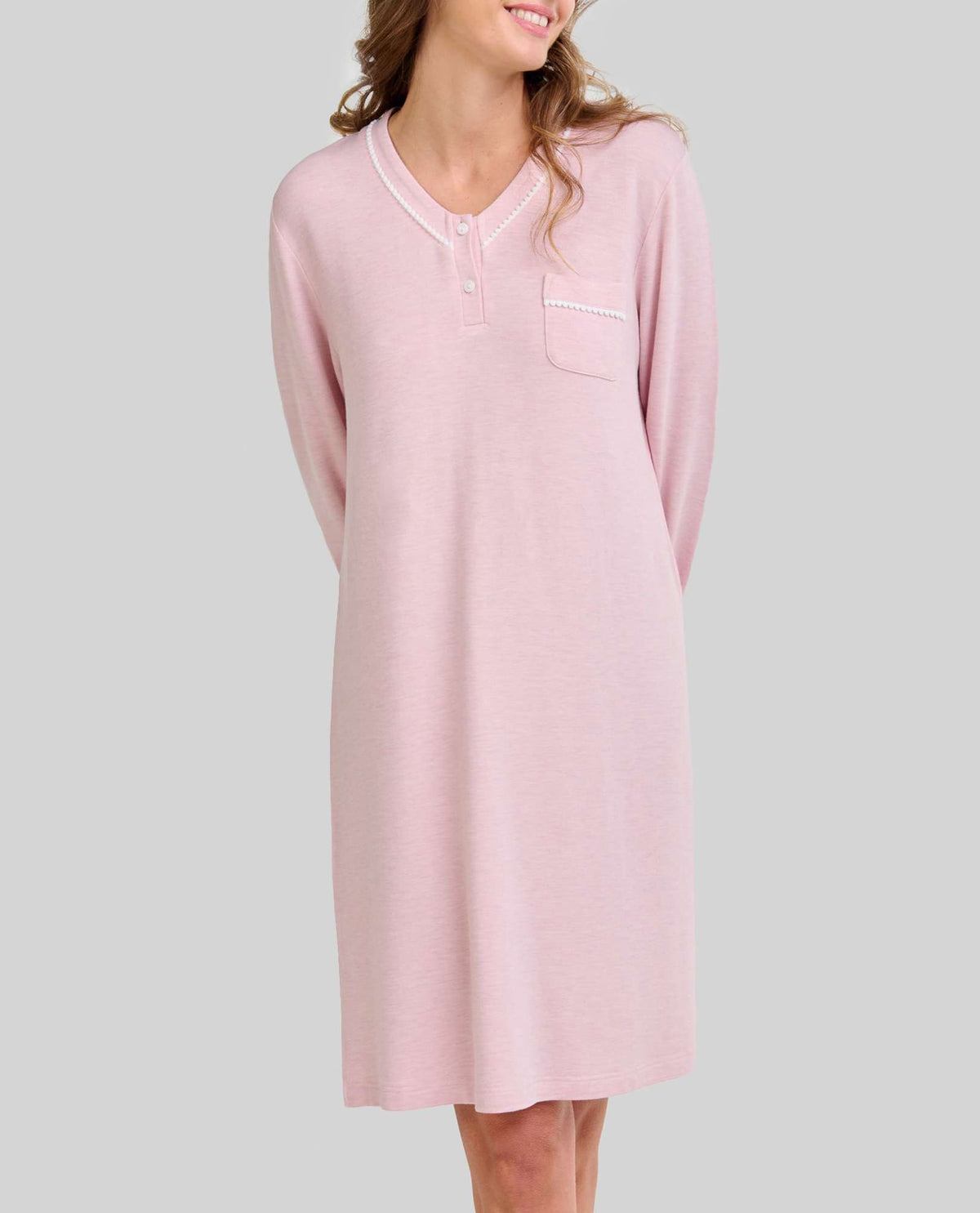 Mujer posa con camisón rosa vigoré de manga larga, bolsillo en el pecho y escote abotonado ideal para dormir.