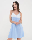 Mujer con camisón de tirantes finos en plana celeste a cuadros, escote pico plumeti con botones, lacito y puntilla.