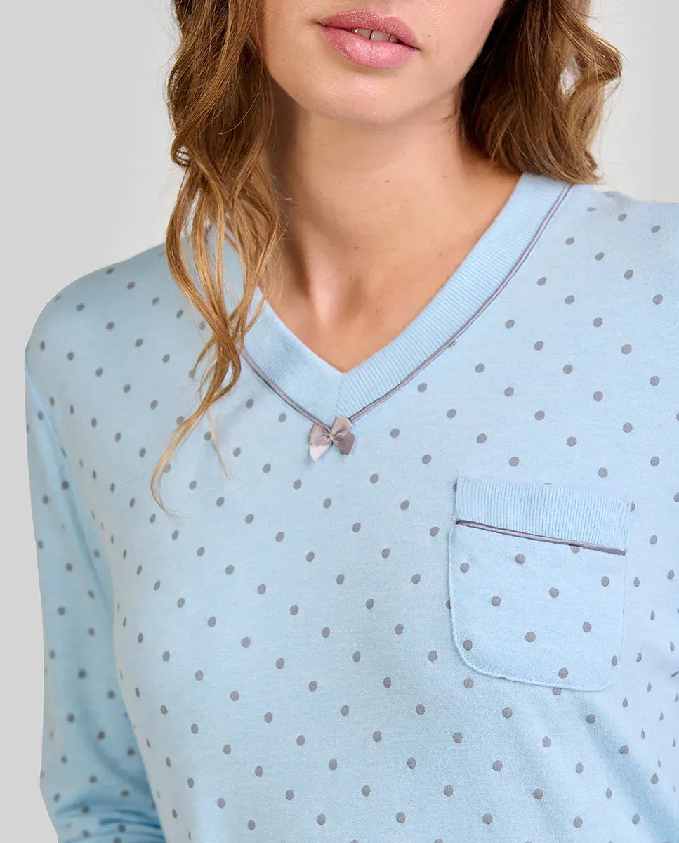 Mujer con camisón celeste de lunares grises, cuello en V, lazo pequeño y bolsillo en el pecho