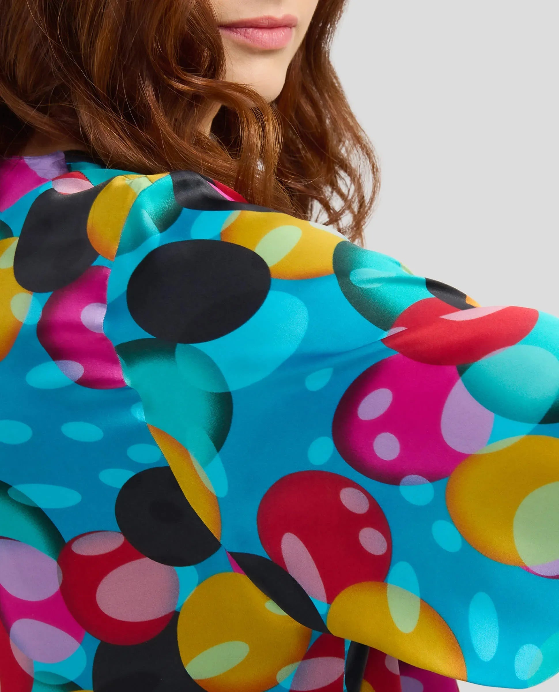 Mujer vestida con vibrante caftán de seda con diseño de círculos superpuestos en múltiples colores
