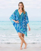 Una mujer luce un caftán azul y blanco con estampado de rayas en la playa, perfecto para el verano