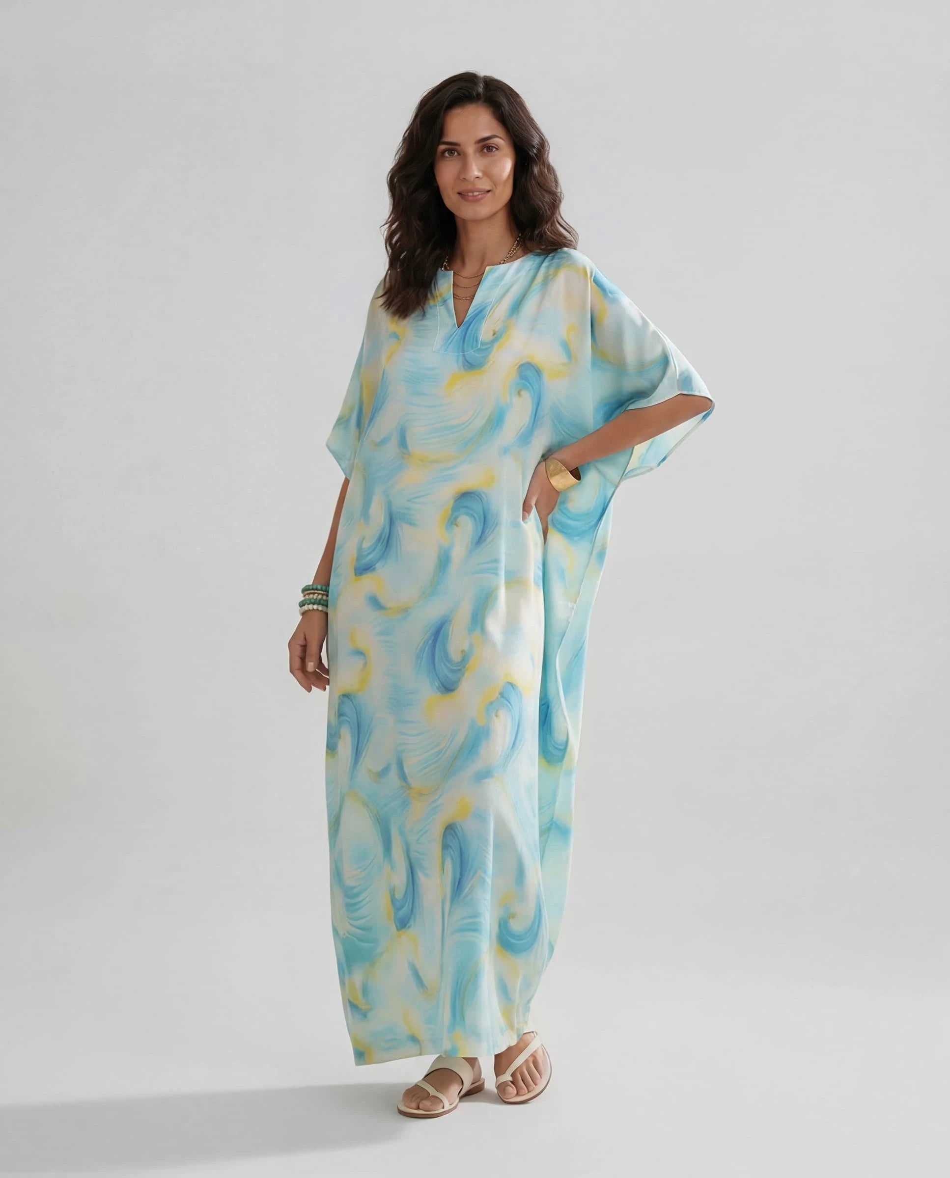 Mujer luce un elegante kaftan largo de seda natural estampado fantasía con con manga mariposa al codo y escote redondo abierto.