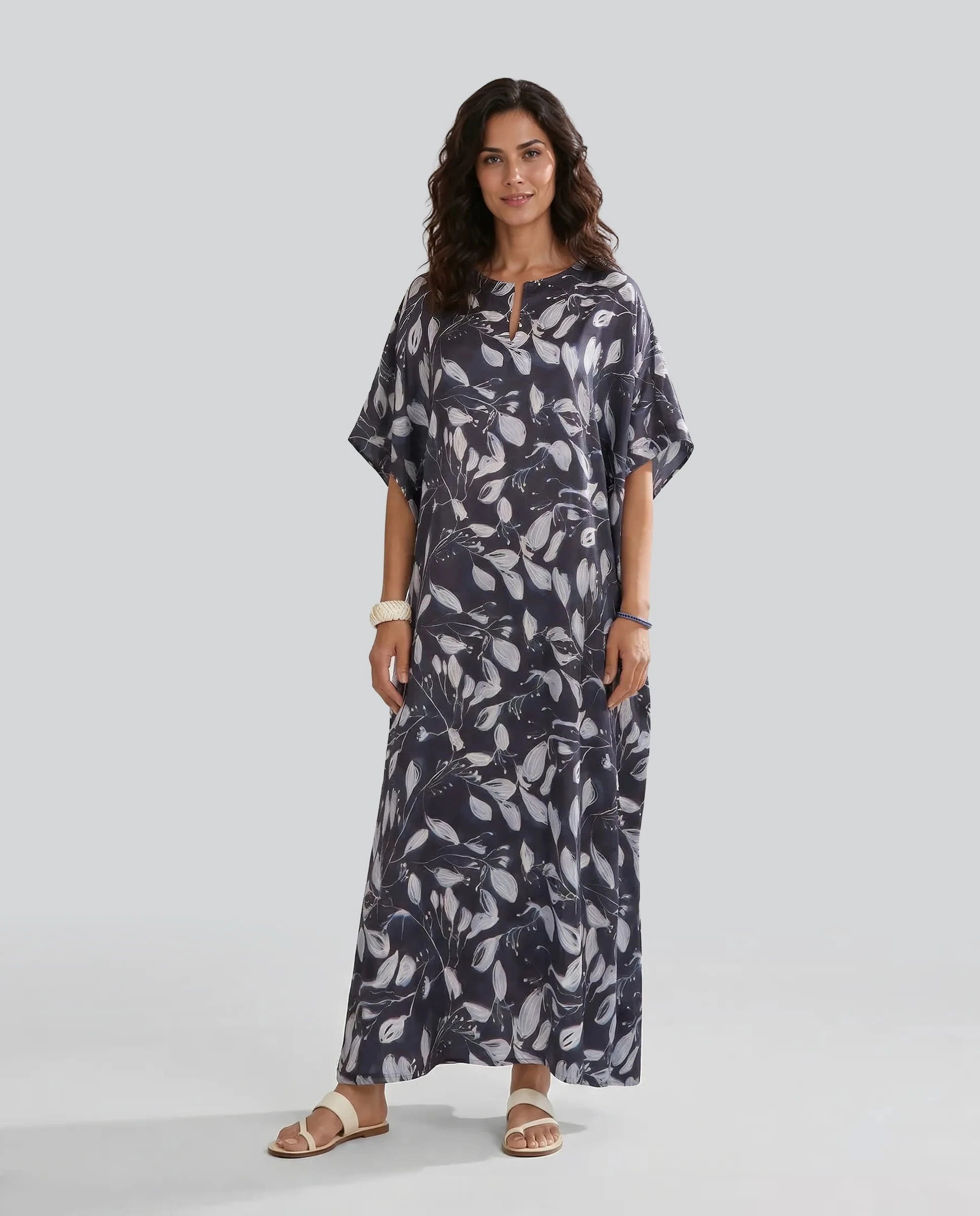 Mujer posa con kaftan largo de verano de seda natural marino con estampado de flores blancas