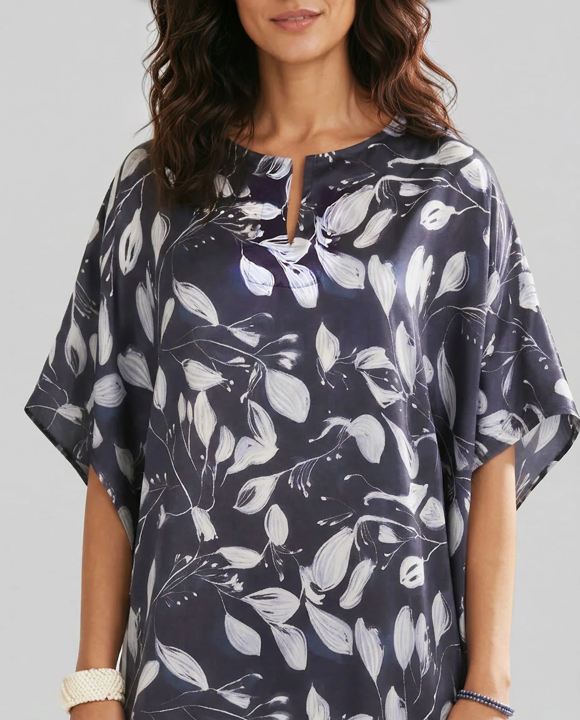 Detalle escote abierto del kaftan de seda estampado marino con flores blancas