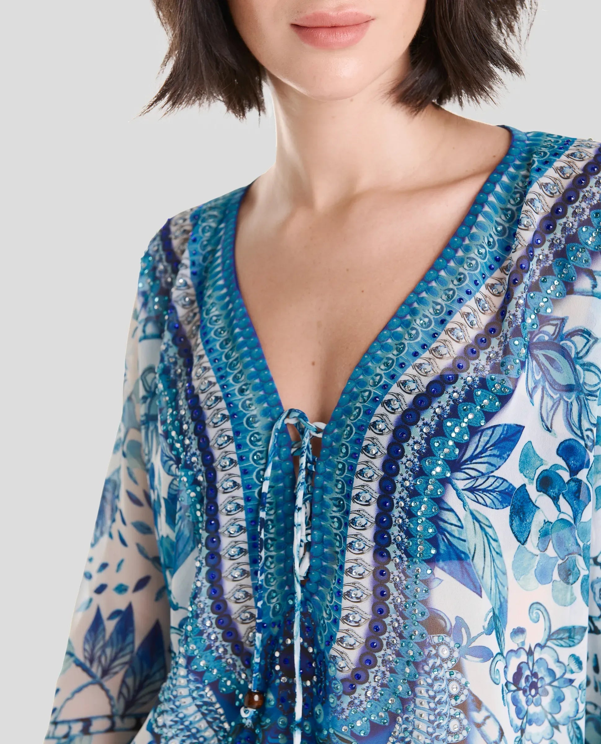 Vista detalle de cuello abierto de kaftan azul corto con pedrería