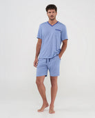 Hombre luce pijama fresco de verano de punto azul con cuello pico y bolsillo en contraste, cintura ajustable