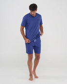 Hombre viste pijama azul veraniego con estampado de cochecitos, bolsillos y cintura ajustable