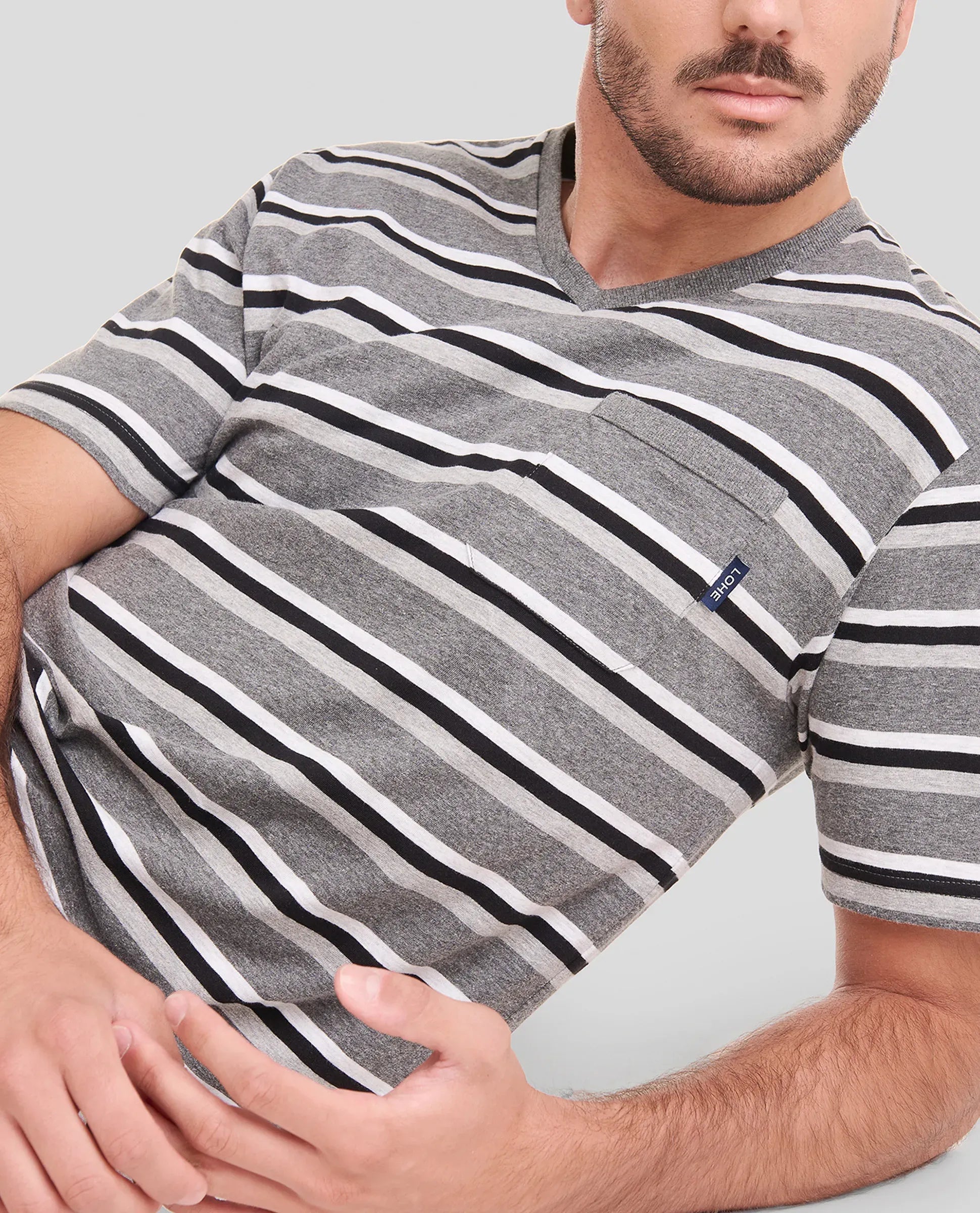 Hombre relajado posa con su pijama veraniego de manga corta de rayas grises y blancas