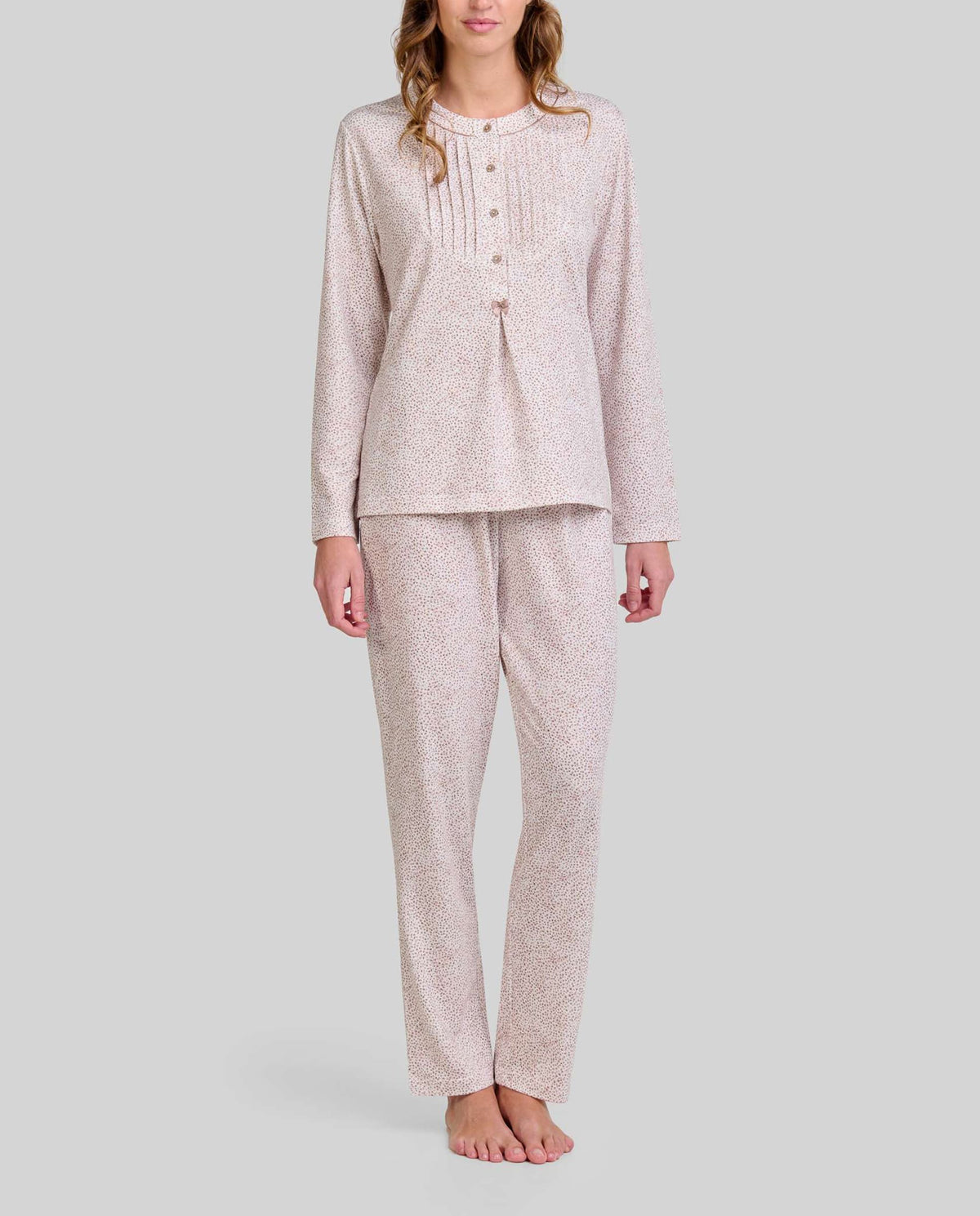 Mujer posando con sutil y elegante pijama de manga larga y pantalón de estampado floral camel.