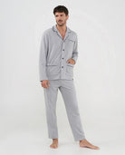 Hombre con pijama gris claro de manga larga, ribetes vivo negros y botones frontales, ideal para dormir.