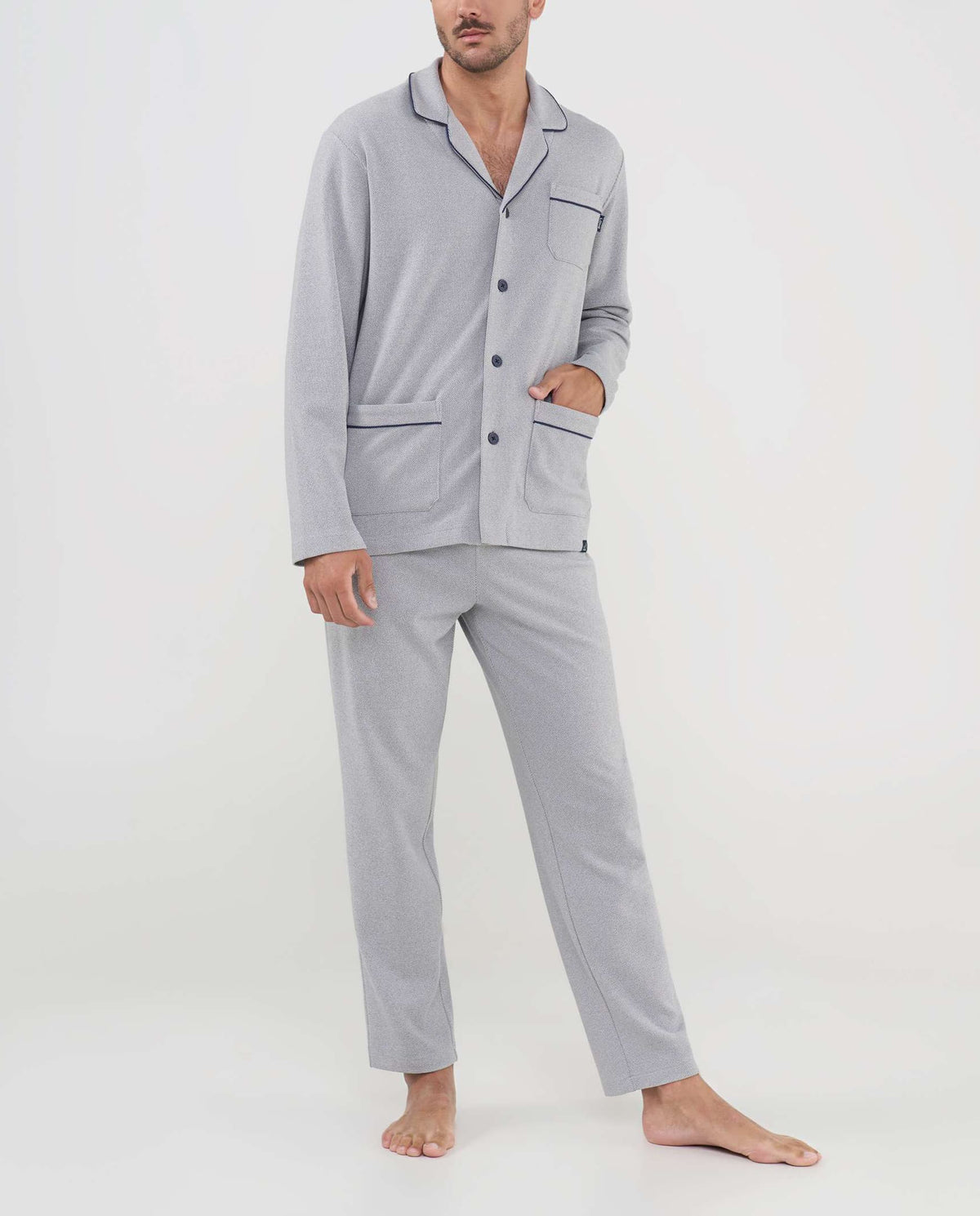 Hombre con pijama gris claro de manga larga, ribetes vivo negros y botones frontales, ideal para dormir.