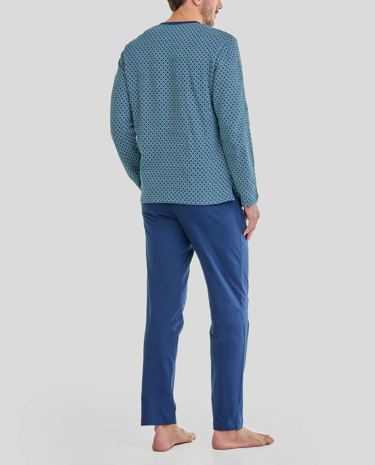 Hombre de espaldas con pijama de invierno de estampado geométrico en tonos azules