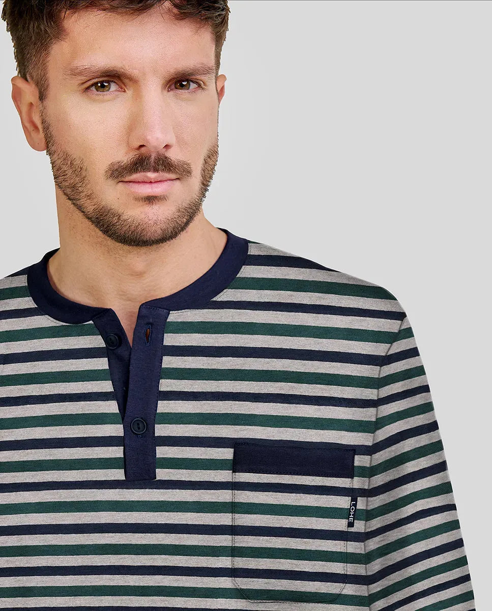 Hombre posando con camiseta de pijama manga larga de rayas marino, gris y verde oscuro, cuello abierto y bolsillo delantero