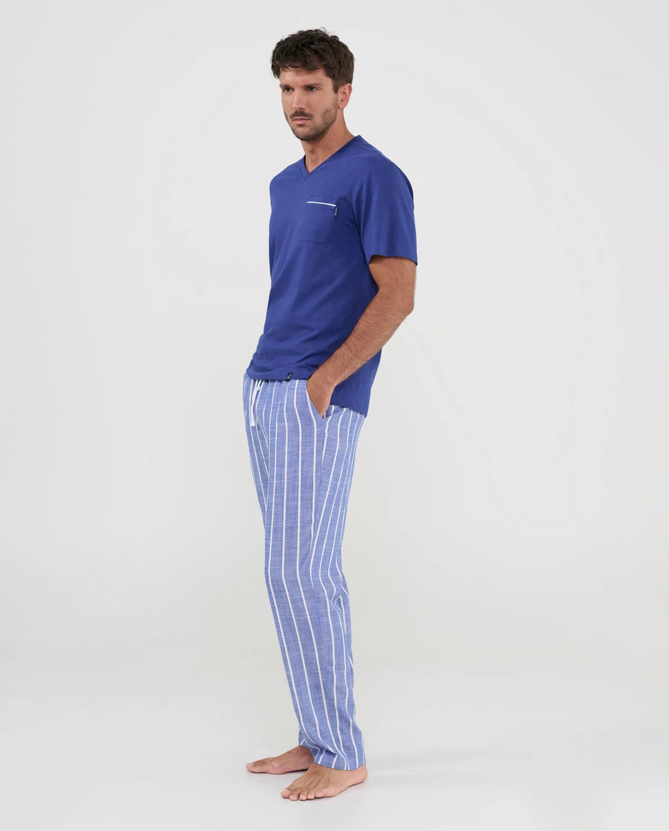 Hombre posa con pijama largo de verano de manga corta, top liso modal azul, cuello pico y pantalón a rayas con bolsillos