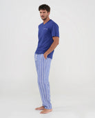 Hombre posa con pijama largo de verano de manga corta, top liso modal azul, cuello pico y pantalón a rayas con bolsillos