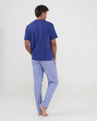 Hombre de espaldas con pijama azul de verano de pantalón largo a rayas y camiseta modal lisa a juego