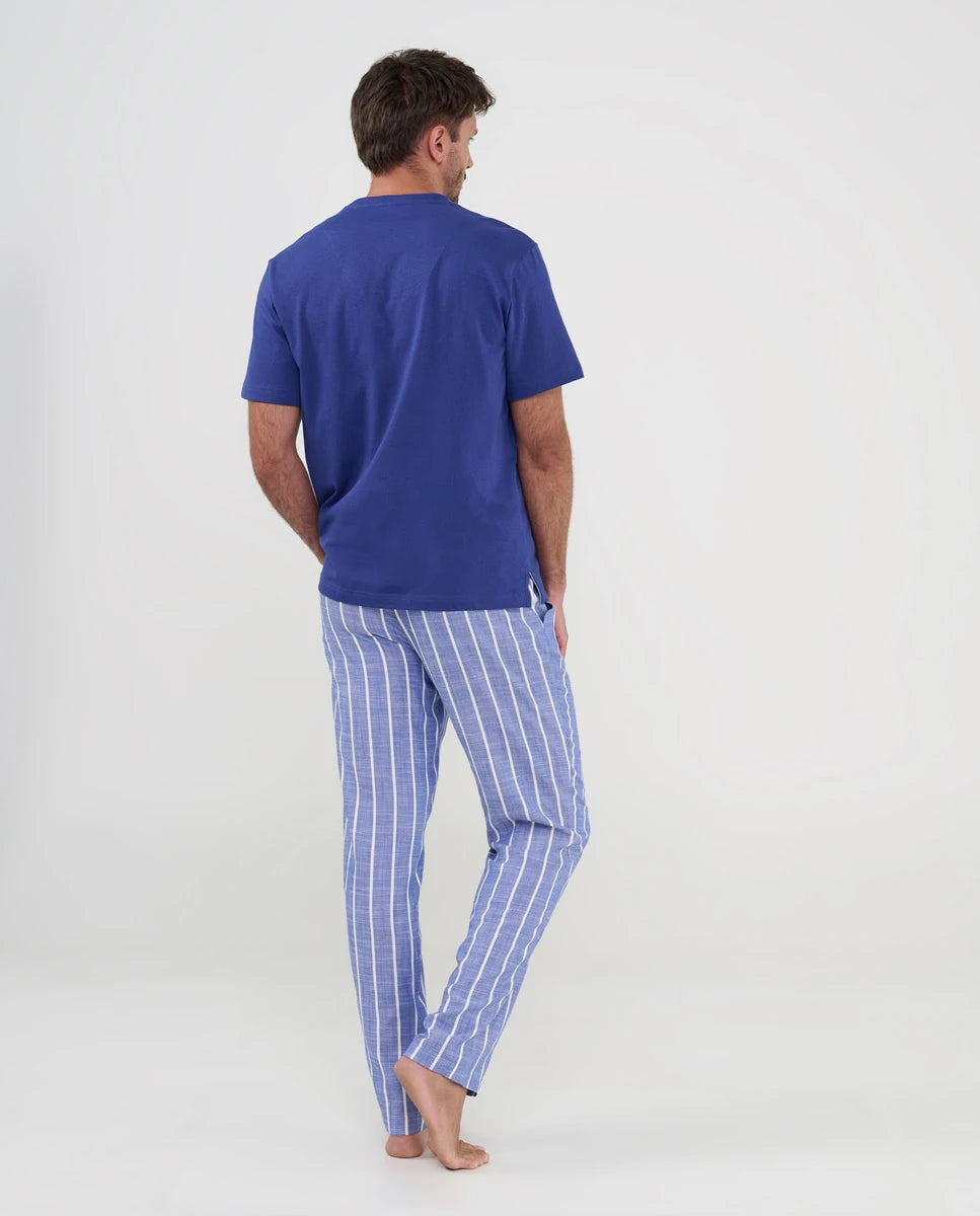 Hombre de espaldas con pijama azul de verano de pantalón largo a rayas y camiseta modal lisa a juego