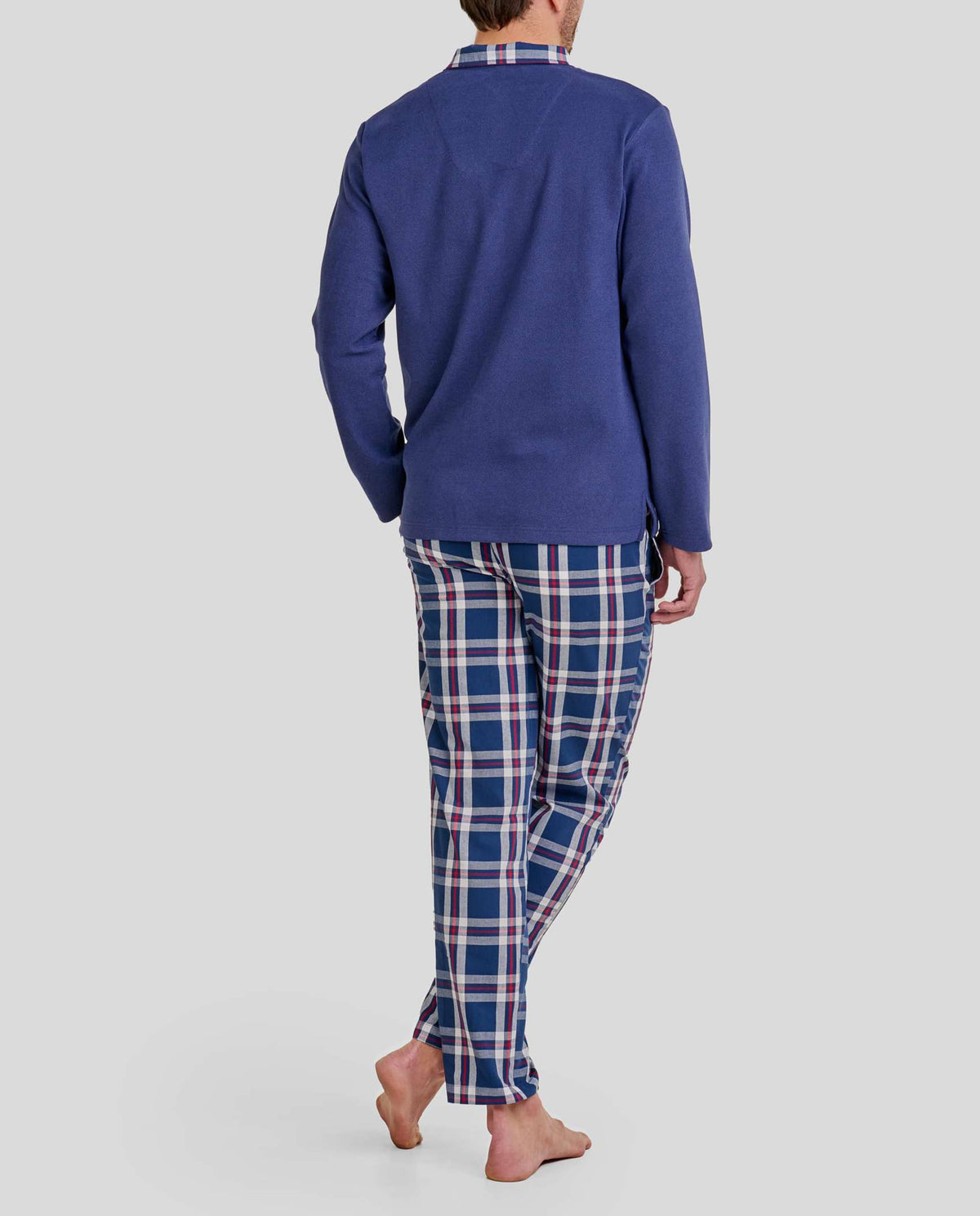 Hombre posa de espaldas con pijama largo de invierno con top azul y pantalón de cuadros con bolsillos a conjunto