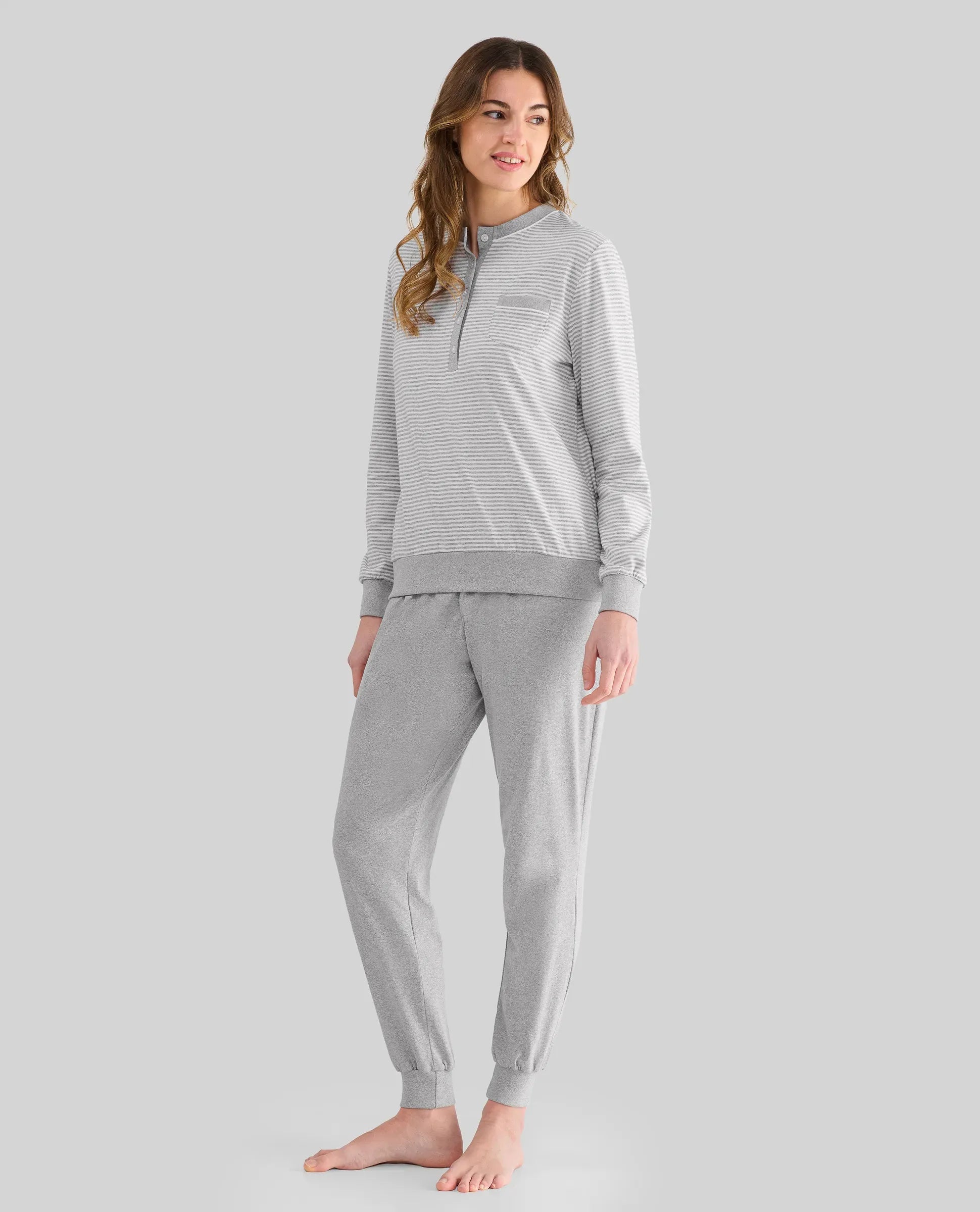 Mujer con pijama largo a rayas grises y cuello pata en el top y pantalón largo vigoré gris