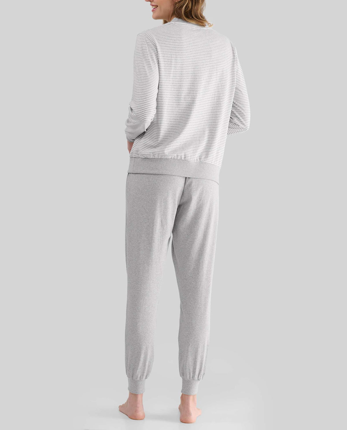 Mujer de espaldas con pijama de invierno gris con top a rayas y puños elásticos