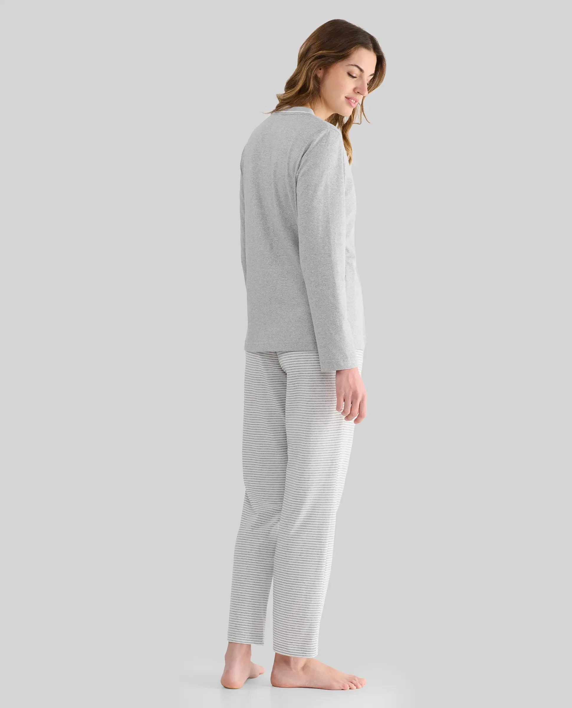 Mujer de perfil con pijama de invierno gris y pantalón de rayas a juego