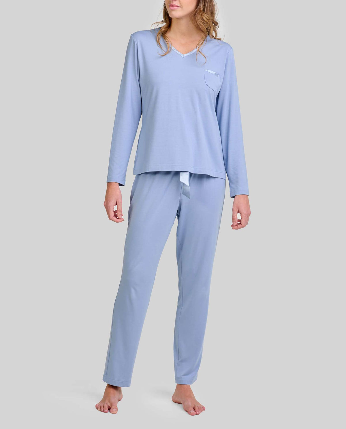 Mujer con pijama largo en tejido modal azul acero con escote pico y detalles en raso