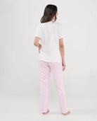 Mujer de espaldas con pijama largo de verano camiseta manga corta blanca y pantalón estampado rosa